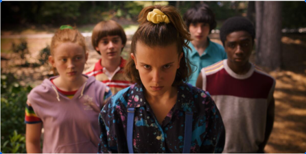 A group of five young teens lined up in a triangle formation. The one in front is El, on her face is a mad expression. And the friends behind her all look at her with a confused face. 