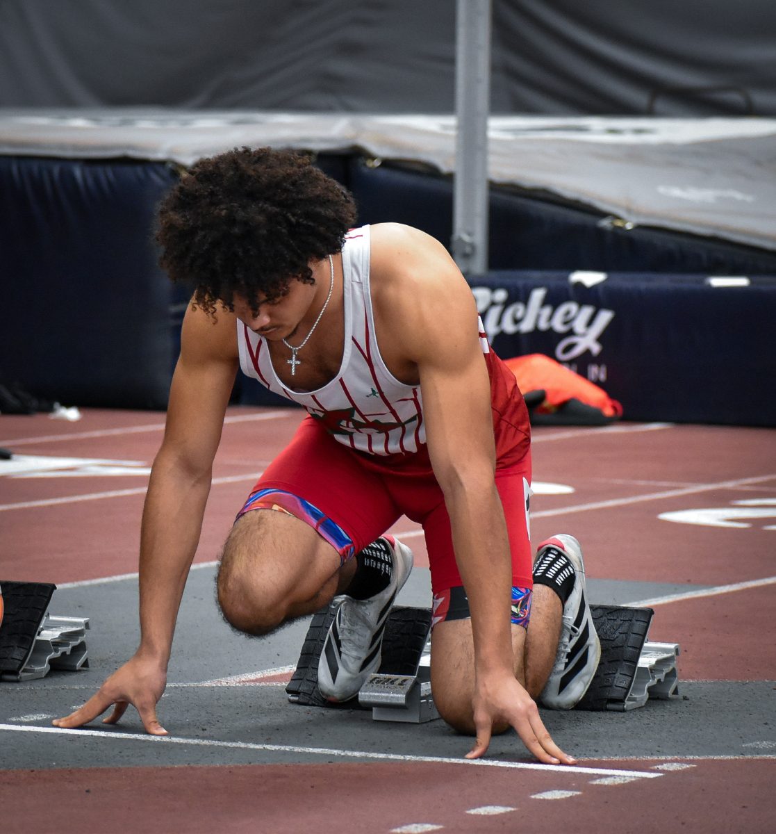 Trenton Coles kneels at the starting line at Anderson's first track meet of the spring season. Coles placed third in a crowded field of runners.