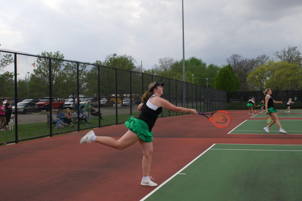 Audrey Strait hits a serve in a home tennis match.